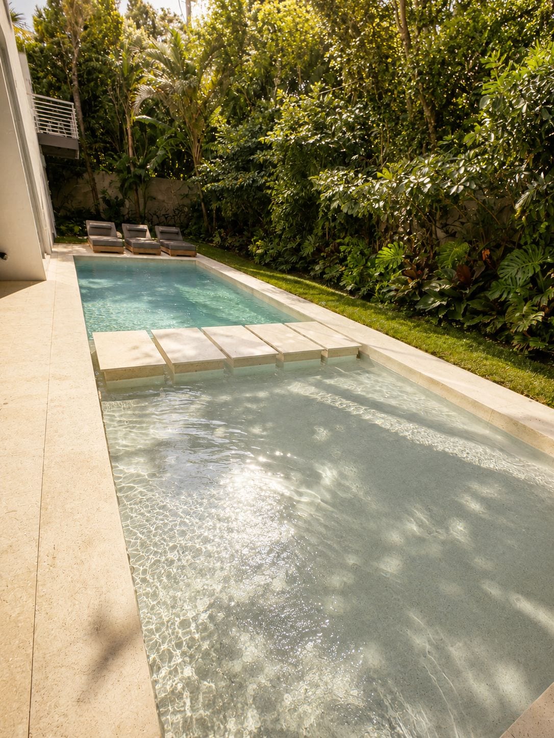 A long stone pool framed by tropical green, the water still in the afternoon light