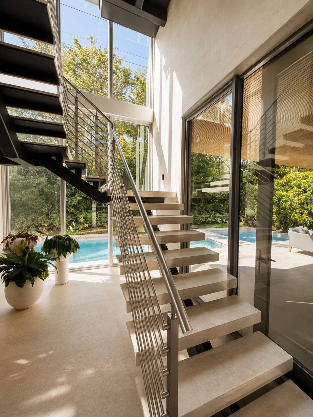 The floating stone-and-steel stair against full-height glass to the garden