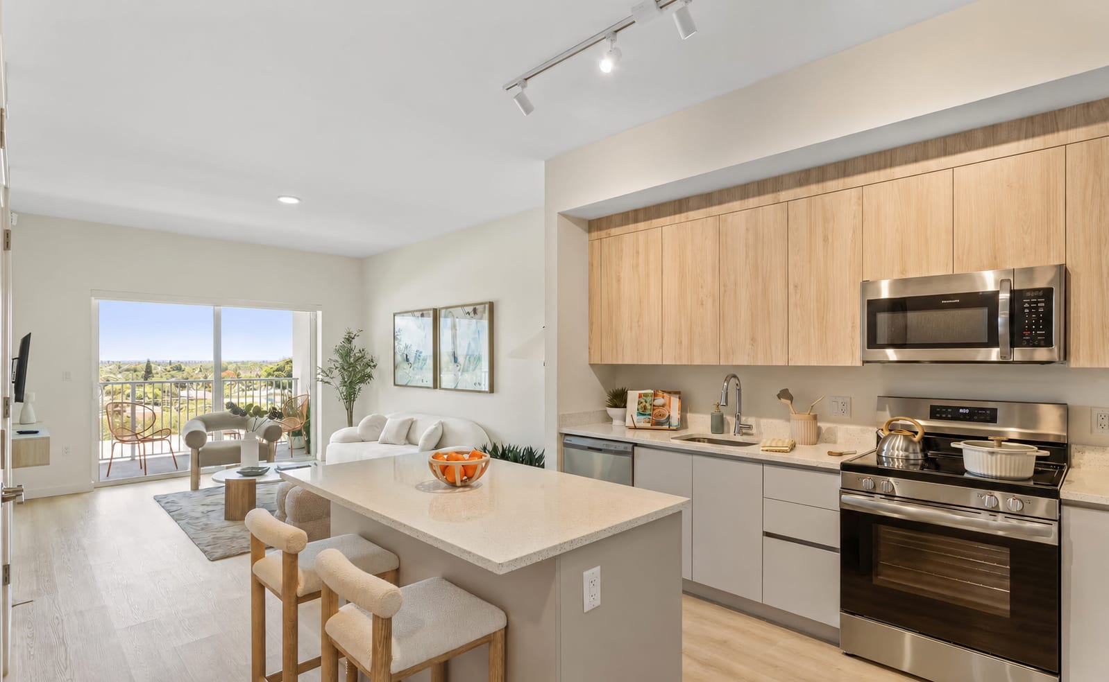 An apartment unit at Deco Green — open kitchen, island seating, the living room and balcony beyond