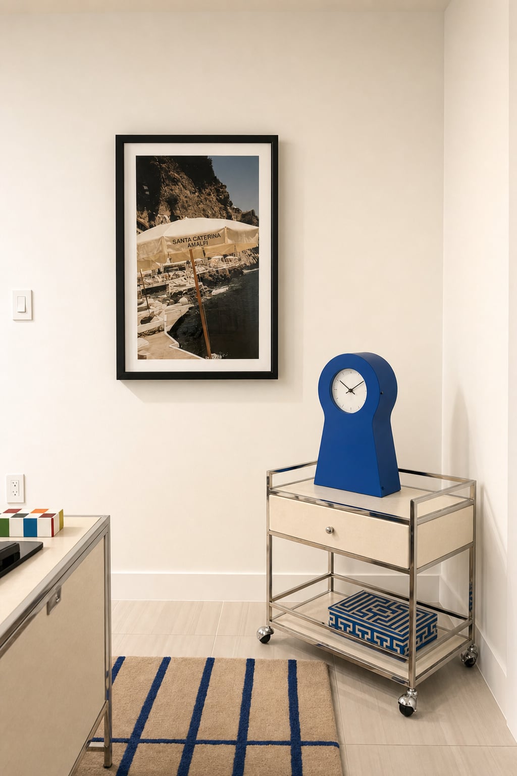 The entry — a cobalt lacquer clock on a mirrored bar cart, a framed coastal print