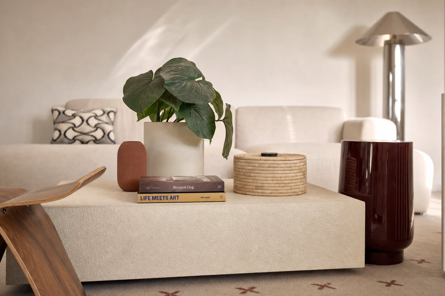 The coffee table, close — books, a woven lidded basket, a fluted burgundy side table